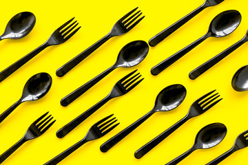 Plastic utilization concept with flatware on yellow background top view pattern