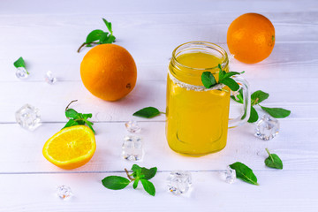 Oranges. Oranges and orange juice in jar with cocktail tube on white wooden background.