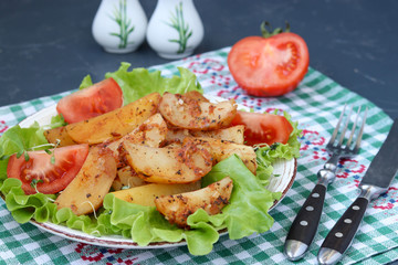Baked potatoes and tomatoes with lettuce on a plate against a dark background