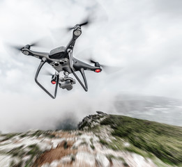 Modern drone flies in the mountains. Dark drone in the air against the backdrop of a mountain landscape.