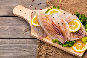 Whitefish Tilapia Fish Raw Fresh Fillet Ready to Cook on Wooden Background. Selective focus.