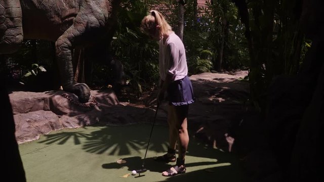 A young woman playing mini golf
