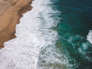 Aerial view of the ocean waves washing on the coast