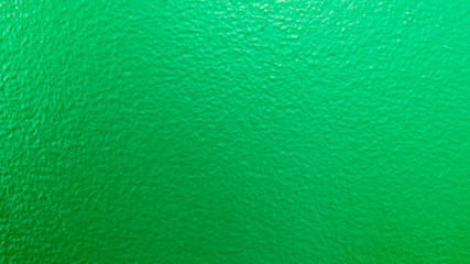 Fototapeta na wymiar Close-up photo of a green textured wall with blue light reflecting on it.