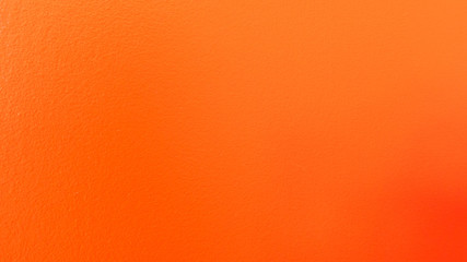 Simple textured wall with a bright orange paint over it.