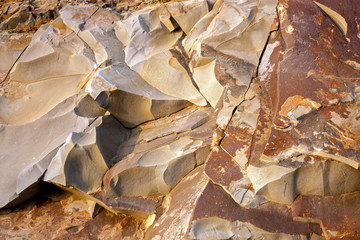 Stone breaks in the rays of sunset. Red and orange stone texture