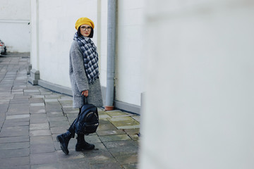 Attractive young girl in glasses in coat and yellow Beret freestyle walking