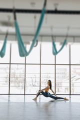 young attractive girl doing fitness exercises with yoga on the floor against the background of panoramic windows