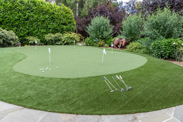 A Green Back Yard Putting Green with Artificial Turf, Multiple Cups, Flags and Putters - 260150601