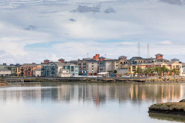 Obraz premium A Waterfront Community Reflected on the Bay in Late Afternoon Sunlight