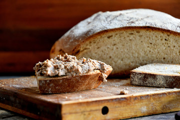Homemade rustic bread and chicken pate on a wooden background.