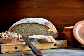 Homemade rustic bread and chicken pate on a wooden background.