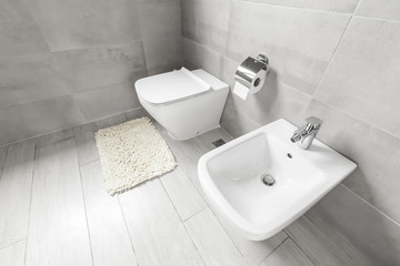 White ceramic bidet and toilet at luxury bathroom interior