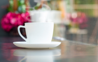 Steaming coffee cup with smoke on marble table in coffee shop