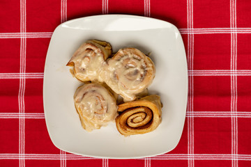 A Plate of Home Made Cinnamon Rolls on a Red Plain Cloth