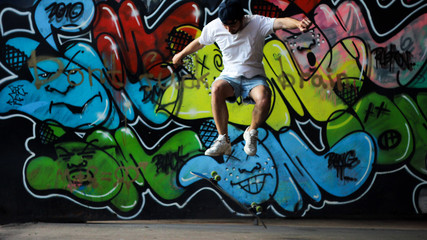 Skater is jumping on skate on ghetto background graffiti