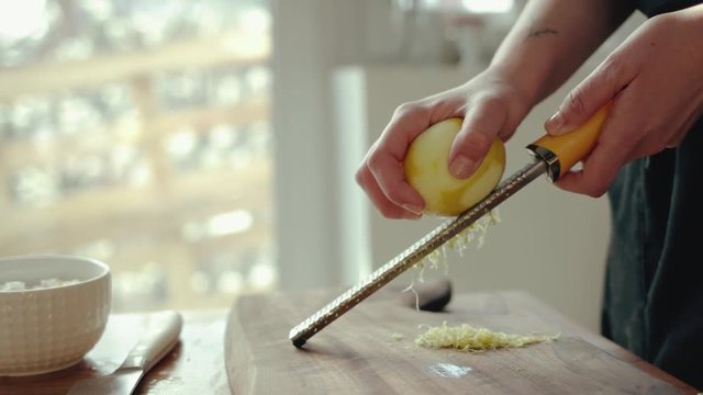 Female chef grinding lemon zest on a wooden board 4k 