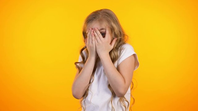 Shocked cute preteen girl peeping through fingers, unexpected surprise, promo