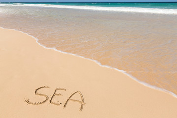 Fototapeta na wymiar Inscription SEA on sandy beach