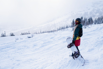 Fototapeta na wymiar Female snowboarder freerider goes to the mountains holding a snowboard.