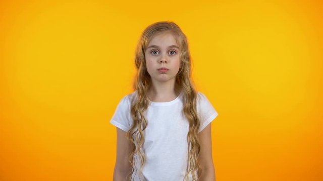 Funny puzzled schoolgirl scratching head and shrugging shoulders, lack of ideas