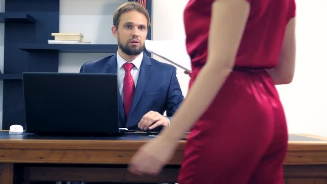 Office flirt. Attractive woman in a red jumpsuit, flirting at the table with her colleague.