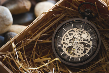 Fototapeta na wymiar Pocket watch winder on natural wheat straw in a wooden box. Concept of vintage or retro gift.