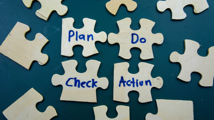 Obraz premium Wooden jigsaw puzzle with text Plan,Do,Check,Action (PDCA Cycle). Quality improvement in business concept.