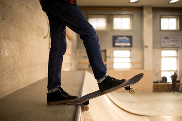 Low section of unrecognizable skater standing on ramp ready to do stunts in extreme park, copy space