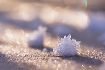 Lumps of frost crystals on a frost-covered wooden surface in the morning sun. The crystals of frost in the open air in the glare of the sun.