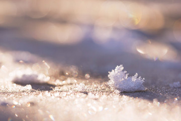 Lumps of frost crystals on a frost-covered wooden surface in the morning sun. The crystals of frost in the open air in the glare of the sun.