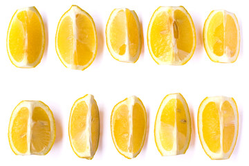 A set of quarters of ripe lemon on an isolated belm background. Lemon slices arranged in several rows on a white background. Top view on sliced lemon close-up.