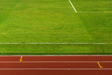 green grass field texture for sport and soccer or football with red brown white line running lane background