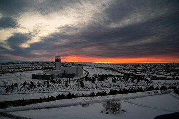 Naklejka premium Beautiful sunset with dramatic clouds behind a church in the snow