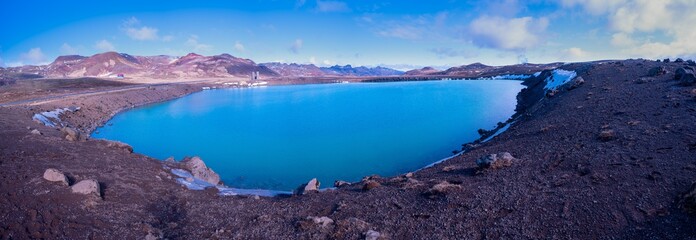 Fototapeta na wymiar Panorama shot of a water filled volcanic crater in mountain landscapes on a sunny day