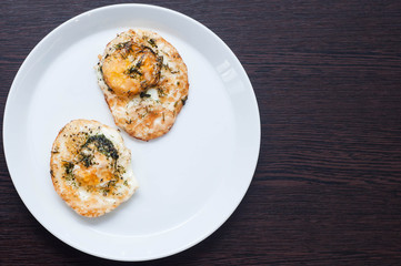 Two fried chicken eggs with greens on a white tray on a wooden table as ideal as a breakfast