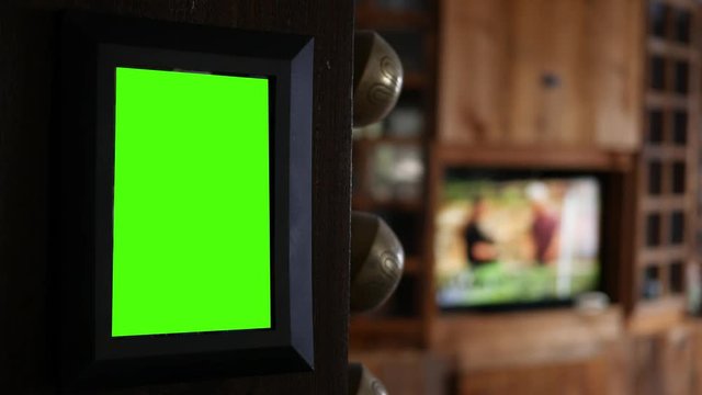 Green screen picture frame hanging on pillar in living room with TV playing in background