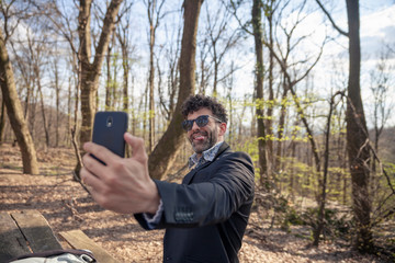 one young man, using smartphone to make a selfie, outdoors in nature.