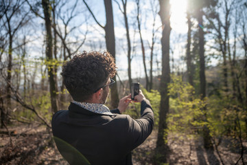 one young man, rear view. making a selfie in forest outdoors.