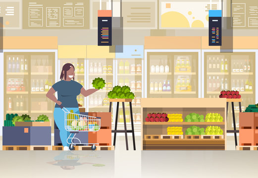 fat obese woman with shopping trolley cart choosing vegetables and fruits weight loss concept overweight african american girl supermarket customer grocery shop interior horizontal full length
