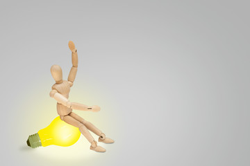 Business Creative and Idea Concept : Wooden figure mannequin sitting on yellow light bulb and put hand up over head.