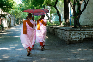 nun with pink robe and umbrella,  in the streets of Mandalay,Myanmar	