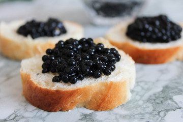 Top view of Tasty Sandwich with black caviar on White marble background.  .Free space for text. Black caviar. Luxurious culinary delicacy.