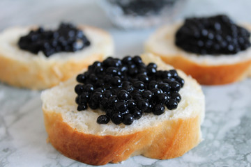 Top view of Tasty Sandwich with black caviar on White marble background.  .Free space for text. Black caviar. Luxurious culinary delicacy.
