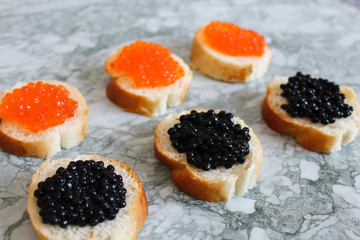 Top view of Sandwiches with red caviar on White marble background .Free space for text. Black caviar. Luxurious culinary delicacy. Close-up salmon caviar. Seafood. Red caviar close-up background. 