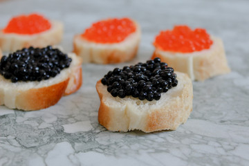Top view of Sandwiches with red caviar on White marble background .Free space for text. Black caviar. Luxurious culinary delicacy. Close-up salmon caviar. Seafood. Red caviar close-up background. 