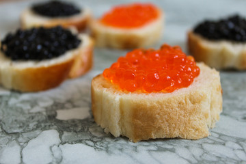 Top view of Sandwiches with red caviar on White marble background .Free space for text. Black caviar. Luxurious culinary delicacy. Close-up salmon caviar. Seafood. Red caviar close-up background. 