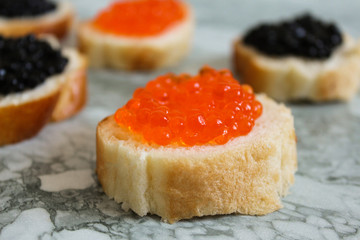 Top view of Sandwiches with red caviar on White marble background .Free space for text. Black caviar. Luxurious culinary delicacy. Close-up salmon caviar. Seafood. Red caviar close-up background. 