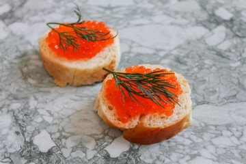 Top view of Sandwiches with red caviar on White marble background .Free space for text. Black caviar. Luxurious culinary delicacy. Close-up salmon caviar. Seafood. Red caviar close-up background. 