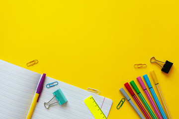 School supplies on yellow background. Back to school concept with space for text. Top view. Copy space. School office supplies.Creative desk with colourful stationery. Colored paper clip.